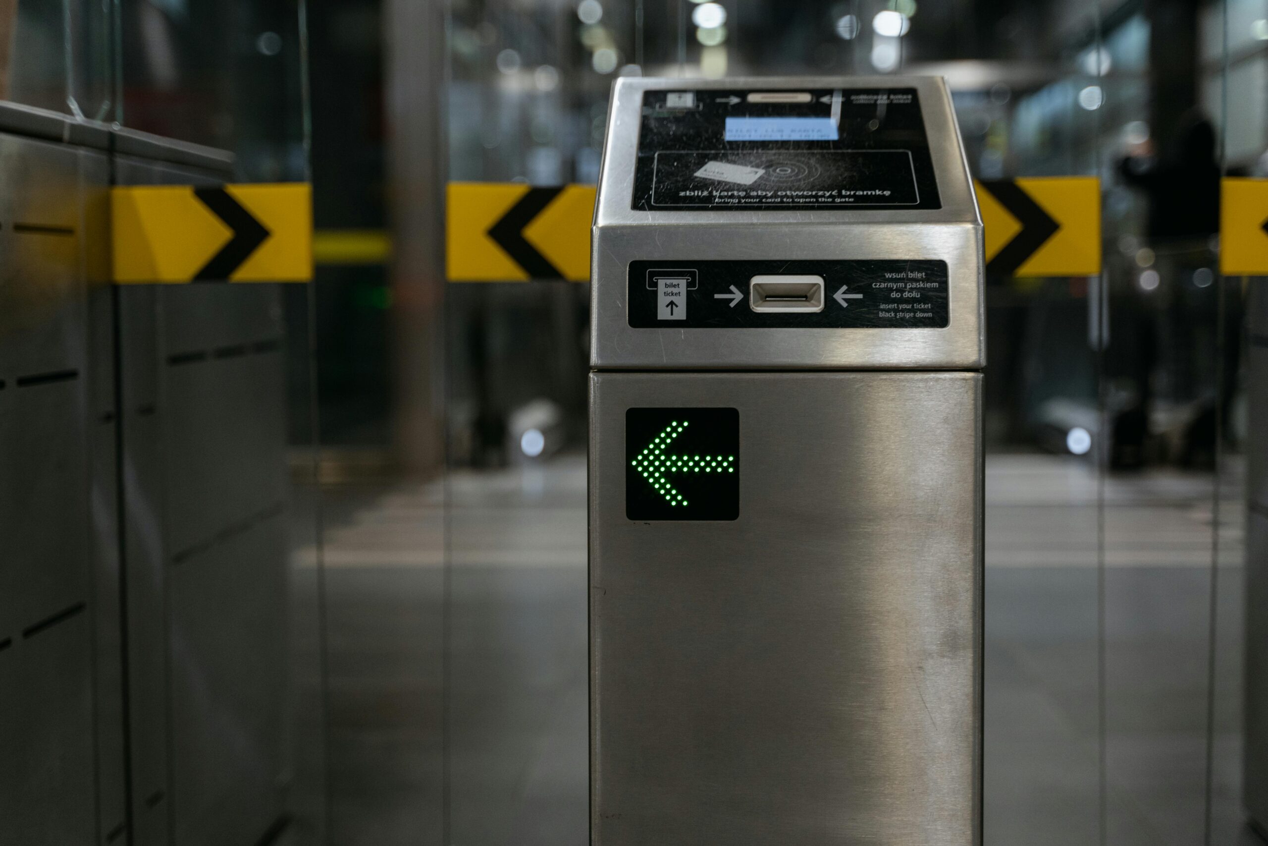 A modern ticket gate with an illuminated arrow for access control in transit systems.